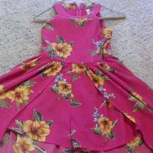 A pink romper with yellow designs and skirt